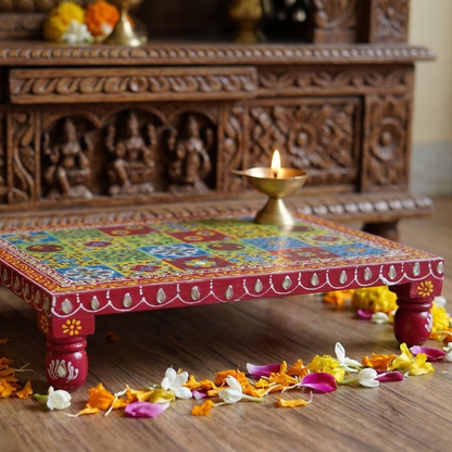 Decorative colorful table with floral arrangements on a wooden floor, with a wooden cabinet in the background.