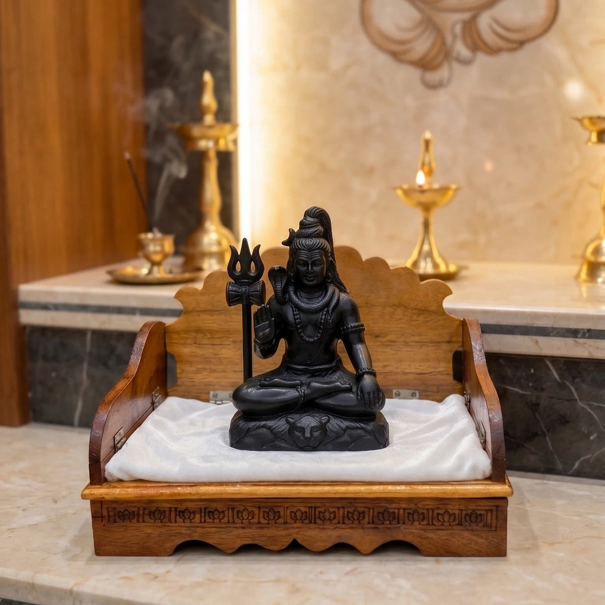 Black statue on a wooden stand with a marble wall featuring a deity illustration in the background.