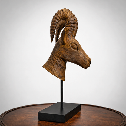 Wooden sculpture of a Dear head on a black stand against a white background