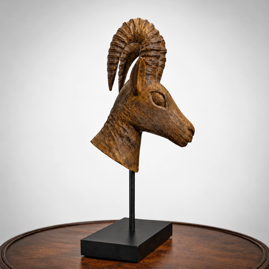 Wooden sculpture of a Dear head on a black stand against a white background