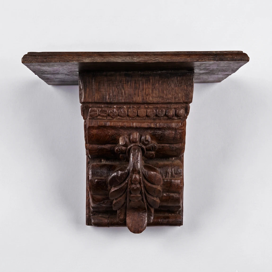 Wooden wall bracket with intricate carvings on a white background