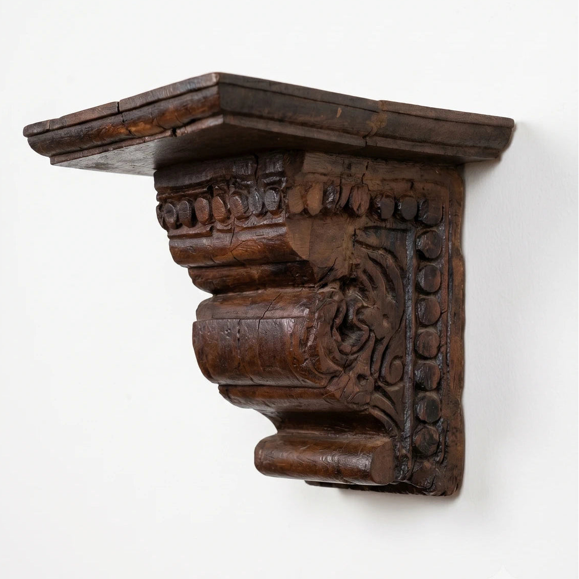 Decorative wooden bracket with intricate carvings on a white background
