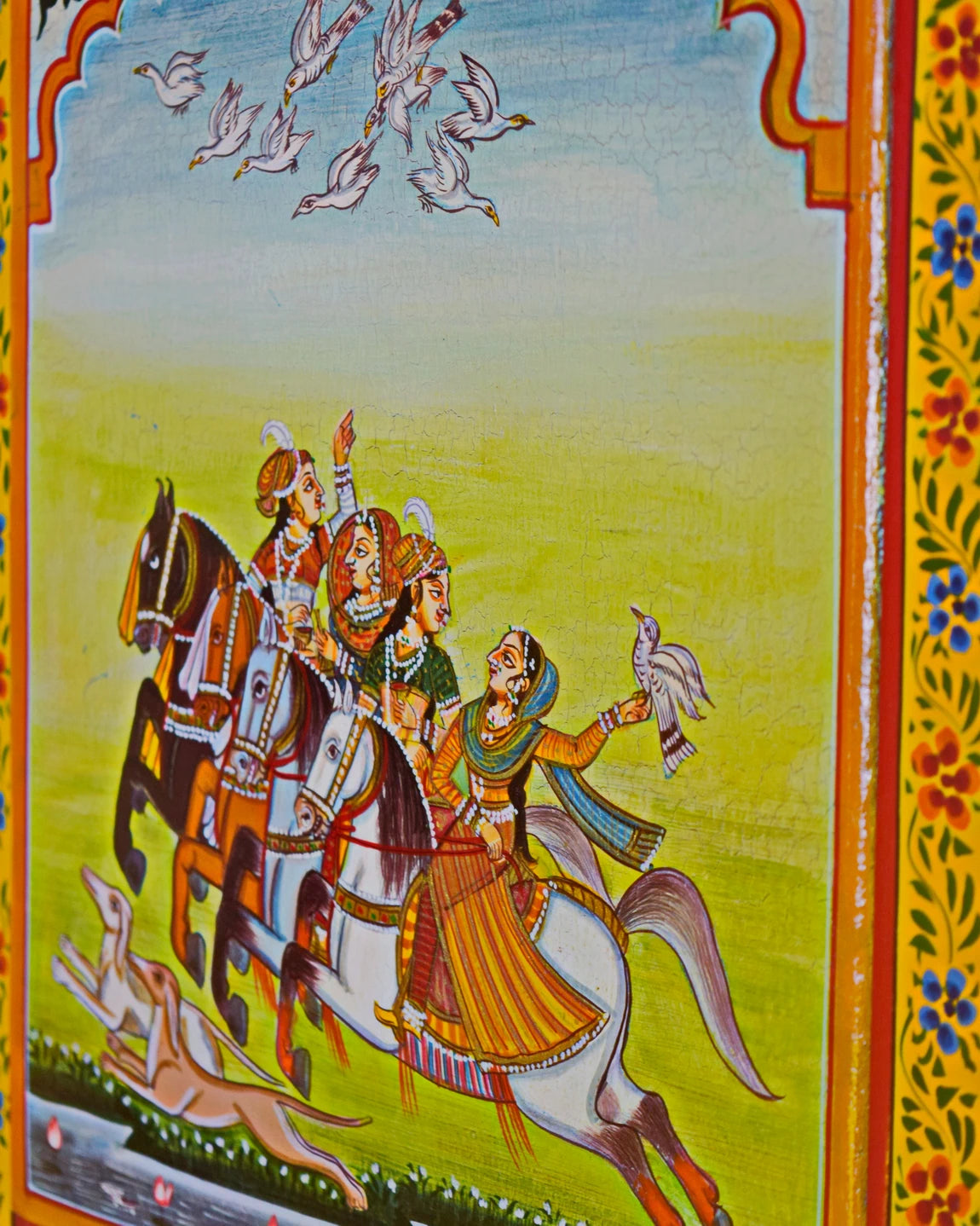 Colorful illustration of people on horseback with birds flying above, framed by decorative elements.