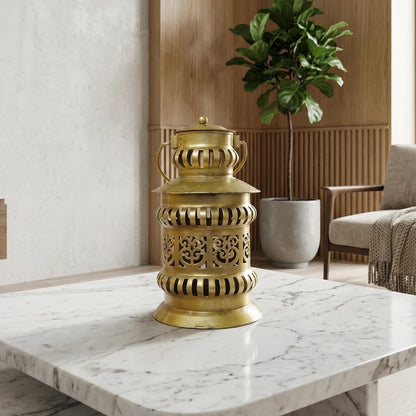 Decorative gold lantern on a marble table with a plant in the background